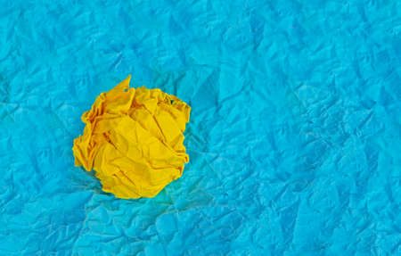 abstract background with yellow crumpled paper with blue crumpled piece of paper, horizontalの写真素材