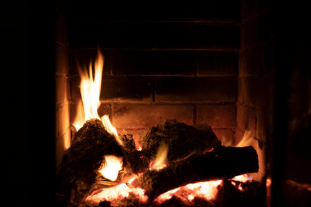 burning fire in a stone fireplace with wood, cozy home