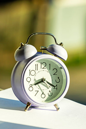 time transfer, alarm clock on the windowsill on a sunny morning, retro photo, Quarantine. vertical...