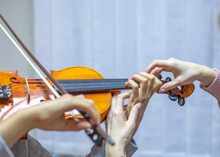 helping the teacher to keep his hand on the violin correctly, placing children's hands when playing the violinの写真素材