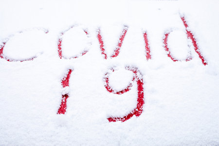 covid-19 written with a finger in the snow on the hood of a red car, lockdown, virus mutationの写真素材