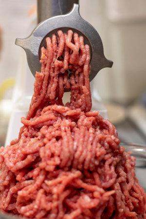 cook minced veal in a meat grinder in the kitchen, blurred background