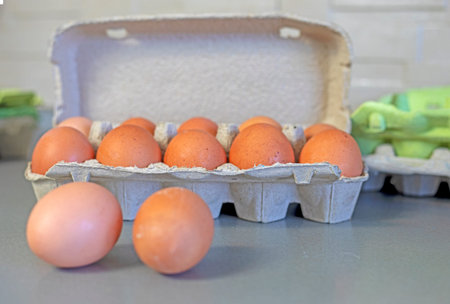 close-up of two eggs on a table near cardboard containers on a light background