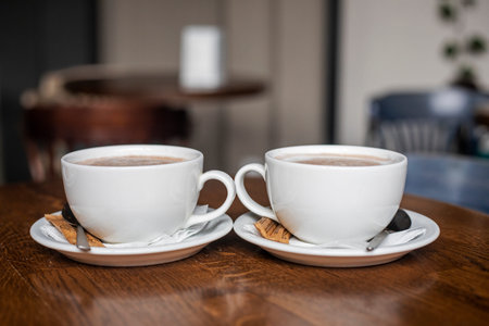 two white cups with hot latte coffee on a wooden table.の写真素材