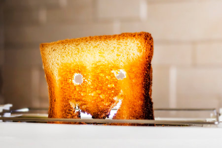 close-up of a smiley face from a hot slice of toasted white bread in a toaster. Horizontalの写真素材