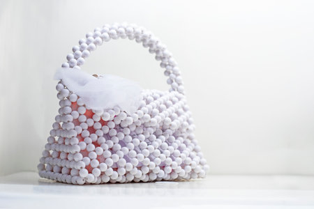 cute trendy white handbag made of white beads on a light backgroundの写真素材
