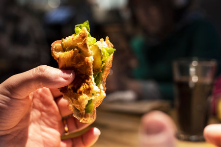 man with his fingers hold a piece of a classic hamburger, horizontalの写真素材