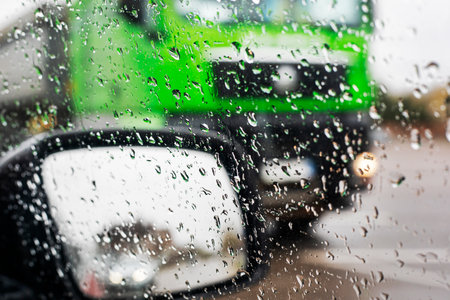 raindrops on the glass near the right mirror of the car, poor visibility on the road. bad weatherの写真素材