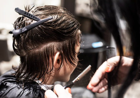 barbershop cuts wet clean hair under a knife to a teenager
