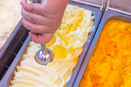woman's hand picking vanilla ice cream by weight with a special ice cream spoonの写真素材