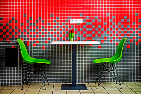 red-gray cafe interior with two green chairs and red tulips at the table. Modern interior trends