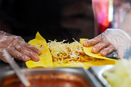male hands in disposable gloves roll vegetarian shawarma into corn pita bread. street foodの写真素材