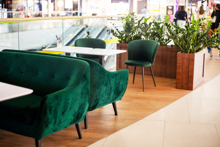 interior with green velvet-covered armchairs with white tables in a cafe in a shopping center