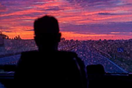 blurred dark silhouette looks through dirty glass at sunrise with clouds. Journeyの写真素材