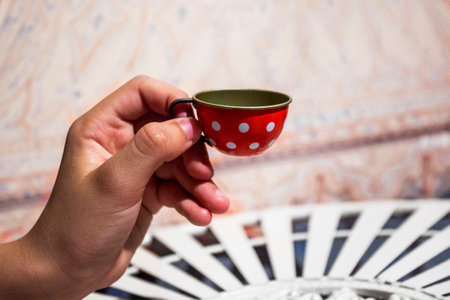 child's hand holds a small orange cup. Fragility of handling. social skillsの写真素材