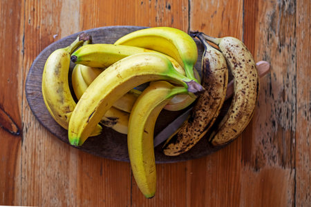 branch of bananas lies on a dish on a wooden table in the living roomの写真素材