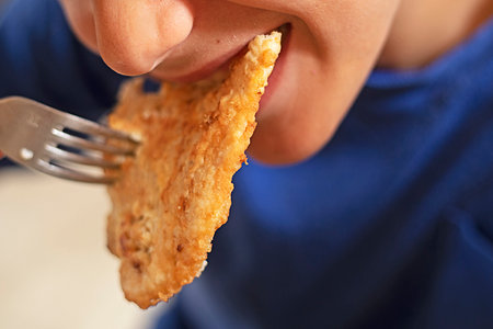 happy boy bites a large piece of fried meat and chickenの写真素材