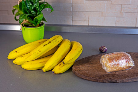 bunch of bananas on the table in the kitchen next to a home flowerの写真素材