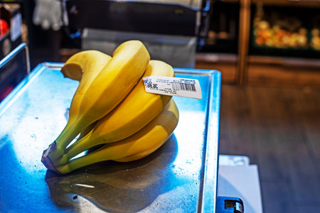 weighing a bunch of bananas on a scale in a supermarketの写真素材