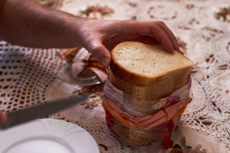 man holds half a piece of bread in his hands to cut it with a knife