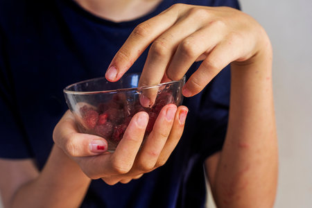 hands of a teenage girl taking raspberries from a glass bowlの写真素材