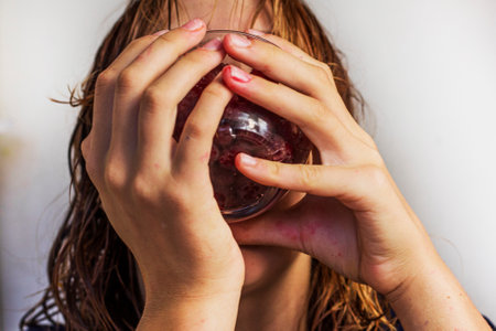 teenage girl eats red raspberries from a bowlの写真素材
