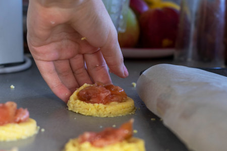girl puts apple jam on shortbread cookies with her hands