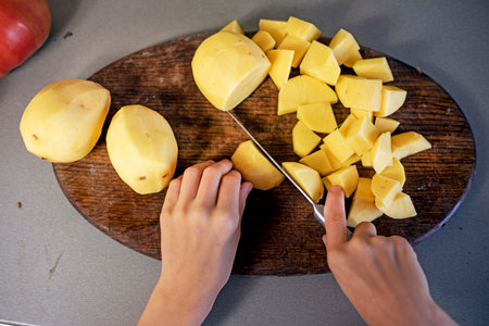 cut potatoes into small pieces with a knife on a cutting board. flatlayの写真素材