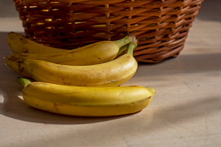 bunch of yellow bananas lie near a rattan basketの写真素材