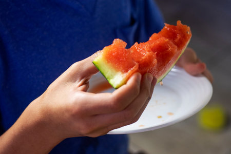boy holding a triangular slice of watermelon in his hands with his mouth open