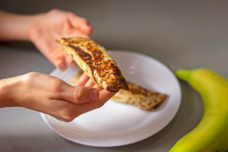take banana pancakes from the plate with your handsの写真素材