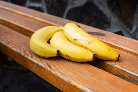 bunch of ripe yellow banana on a wooden surface.の写真素材