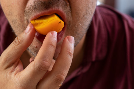 man takes a piece of a yellow homemade tomatoの写真素材
