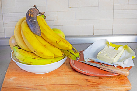 bunch of bananas with apples in a plate with banana oil in the kitchenの写真素材