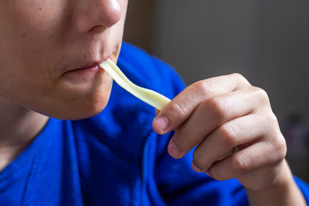boy eats homemade noodles with his long hands, sucking his lips into his mouth