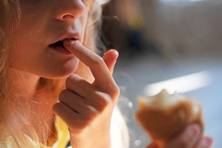 girl eats croissant, removing crumbs from her mouth with her fingerの写真素材
