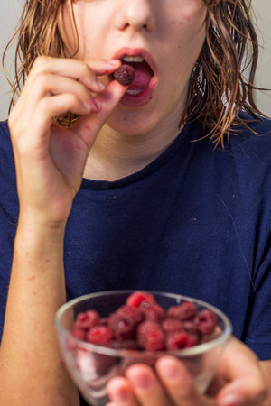 happy teenage girl eats red raspberriesの写真素材