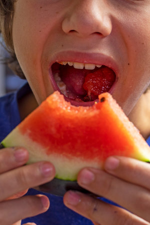 happy boy took a bite of red watermelon from the slice. Watermelon Dayの写真素材