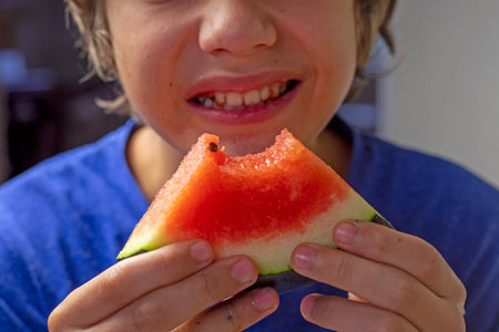 happy boy took a bite of red watermelon from the slice. Watermelon Day