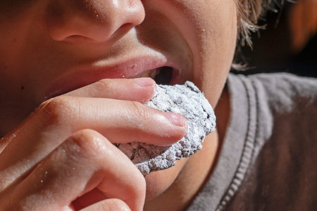 boy eats chocolate cookies sprinkled with sugar