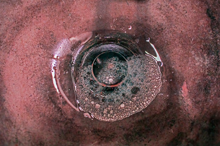 abstract reddish background of liquid pouring through a hole. Plumbing repairの写真素材