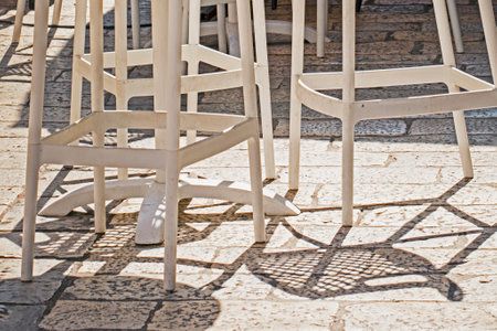 wicker bar stools and table illuminated by the sun at a street cafeの写真素材