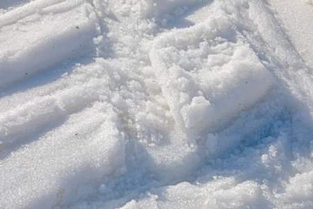 background of white snow with traces of skiers on a sunny dayの写真素材