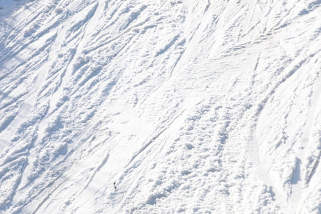 abstract background of white snow with traces of skiers on a sunny dayの写真素材