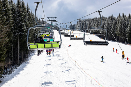Skiers and snowboarders go up the ski slope on a ski lift on a sunny day. Active family vacation. School breakの写真素材