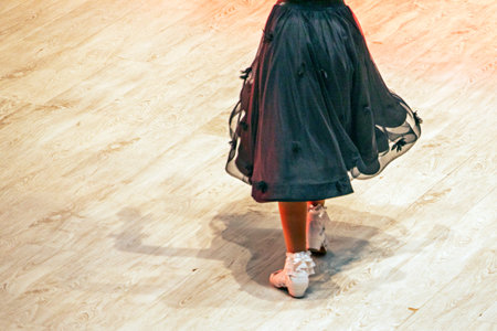 girl in a black dress in dancing shoes on the floor