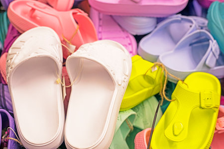 multi-colored rubber summer slippers crocsi for swimming, pool, beach in the store in a container with other slippers. Comfortable shoesの写真素材