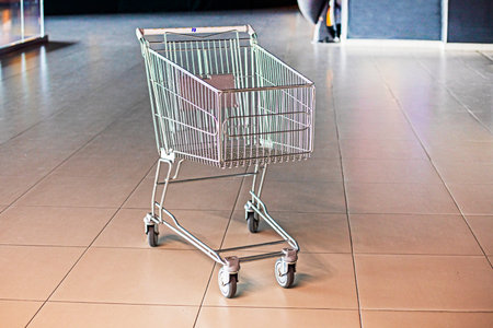 empty iron grocery cart is left near the door to a supermarketの写真素材