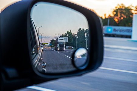 truck in the car's right side mirror while the car is driving in the eveningの写真素材