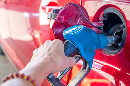 woman is filling up a red car with fuel. Global economic crisis and default